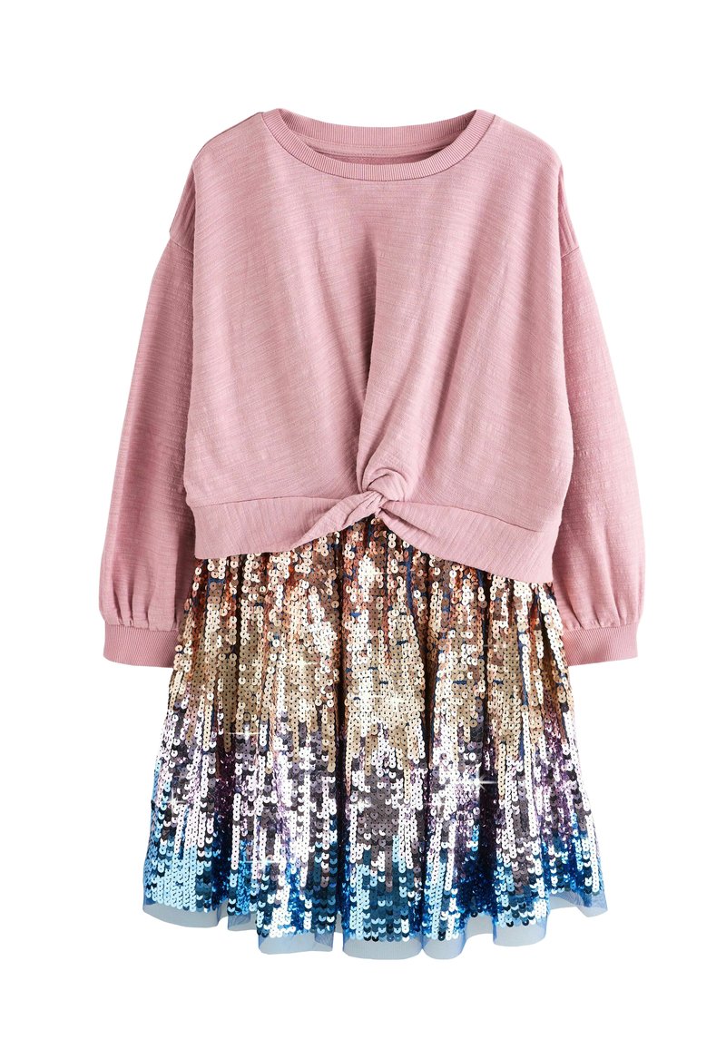 Rosa Langarmpullover mit einem geknoteten Detail an der Taille, ergänzt durch einen schimmernden Paillettenrock, der von Gold zu Blau verläuft.
