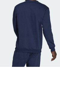 Felpa blu navy con scollatura a girocollo, maniche lunghe e polsini e orlo a coste; realizzata in un tessuto morbido con una texture liscia.