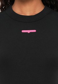 Must mustriba sweatshirt ümaratekkiga ja roosa "tommy jeans" logo õmmeldud vasakule poole. Sile kangastekstuuri.