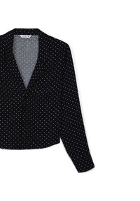 Camicia nera con bottoni, caratterizzata da piccoli pois bianchi, maniche lunghe, colletto a punta e una texture di tessuto liscia.