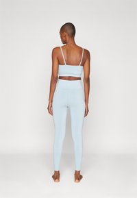 Svetle modrý žebrovaný crop top a odpovídající legíny s tenkými ramínky a obepínajícím designem, který vytváří bezšvový vzhled.