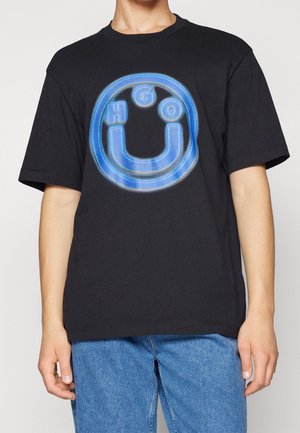 Czarny, oversize'owy t-shirt z dużym niebieskim logo graficznym z literami "HGO" wewnątrz okrągłego wzoru. Krótkie rękawy i okrągły dekolt.