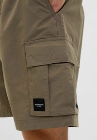 Könnyű szövetből készült khaki cargo rövidnadrág, oldalzsebbel, varrott részletekkel és márkajelzéssel az alsó részen.