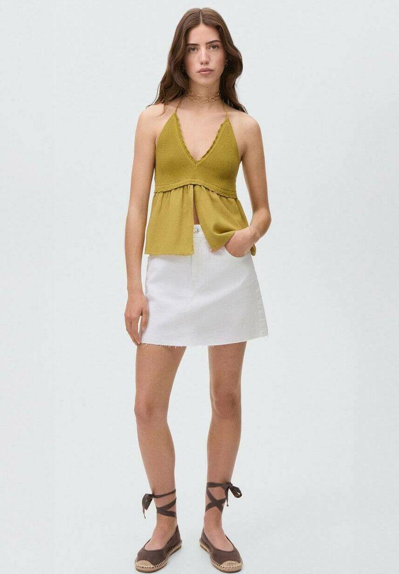 Olivovozelený pletený halter top s hlbokým V-výstrihom a z gathered pásom, v kombinácii s bielou denim mini sukňou a hnedými espadrilkami.