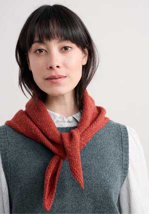 Rust-colored knitted scarf tied at the neck, worn over a gray sleeveless sweater and a white-striped collared shirt. Soft texture.