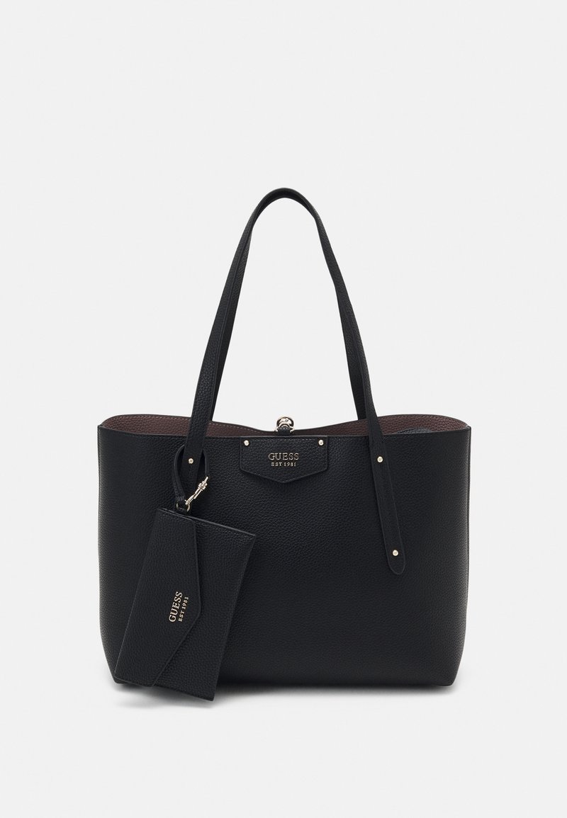 Sac fourre-tout en cuir noir texturé avec longues anses et pochette assortie amovible, toutes deux embossées du nom de la marque "GUESS EST 1981".