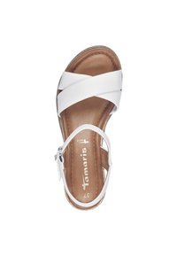 White leather sandal with crisscross straps, a brown insole, and an adjustable ankle strap. Round toe and flat sole design.