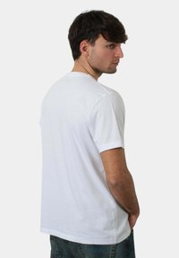 T-shirt bianco a maniche corte con collo a giro, realizzato in cotone morbido, caratterizzato da una vestibilità rilassata e da un design pulito e semplice.