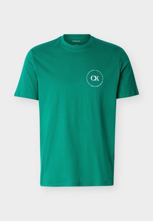 T-shirt vert à manches courtes avec col rond, logo blanc "CK" de Calvin Klein et texte circulaire sur le côté gauche de la poitrine.