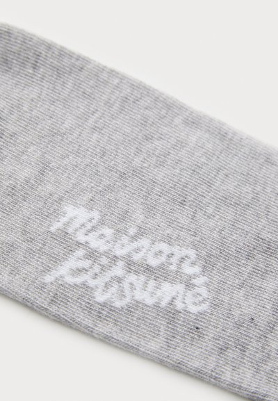 Hallhalli puuvillane sokk, millel on peene tekstuur ja valge broderi tekst "Maison Kitsuné" ääres.