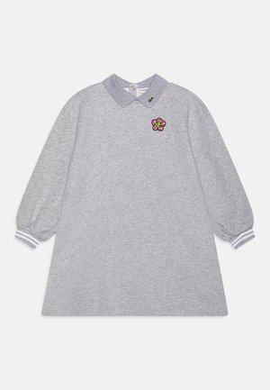 Langærmet grå kjole med ribbet manchetter, en mørkere grå krave med en lille grøn logo og en lyserød blomsterlap på brystet.