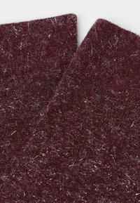 Burgundowy dzianinowy materiał o teksturowanej powierzchni, z srebrnymi akcentami i miękkim, puszystym wyglądem. Zbliżenie na dwa nakładające się kawałki.