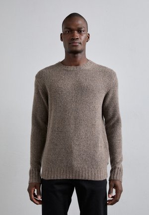 Maglione marrone a maglia con scollatura rotonda, polsini e orlo a costine, caratterizzato da una texture morbida e un tessuto di medio peso. Indossato con pantaloni scuri.