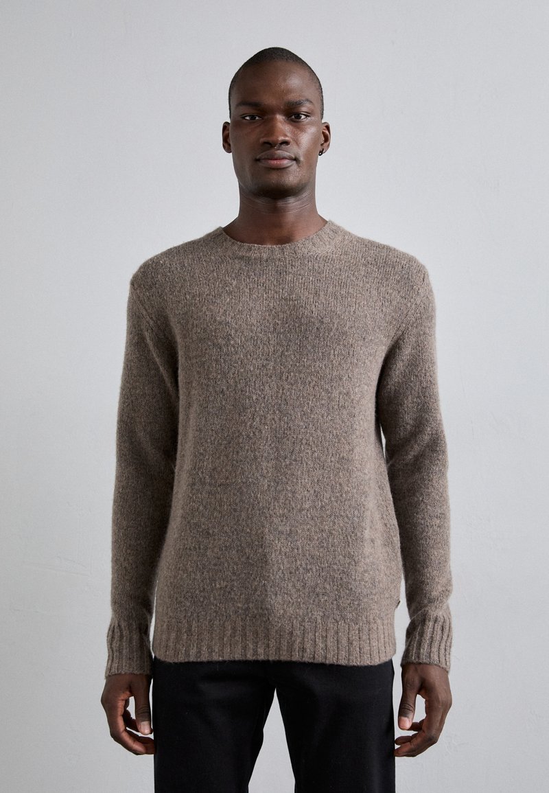 Bruin gebreid sweater met een ronde hals, ribgebreide boorden en zoom, met een zachte textuur en middelzware stof. Draag met donkere broeken.