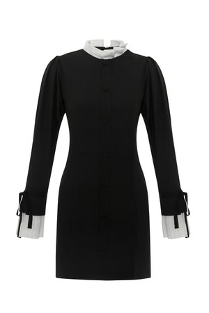Robe noire avec un col blanc haut, fermeture à boutons sur le devant et manches longues dotées de poignets plissés blancs avec des liens. Texture de tissu lisse.
