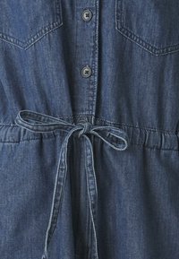 Mørkeblå denimkjole med knappestolpe foran, to brystlommer og innsnørt midje med matchende belte. Glatt tekstur.