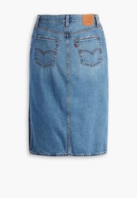 Jupe en denim avec un délavage bleu clair, présentant une coupe droite, une fente arrière et deux poches arrière. Comprend un patch en cuir avec la marque.