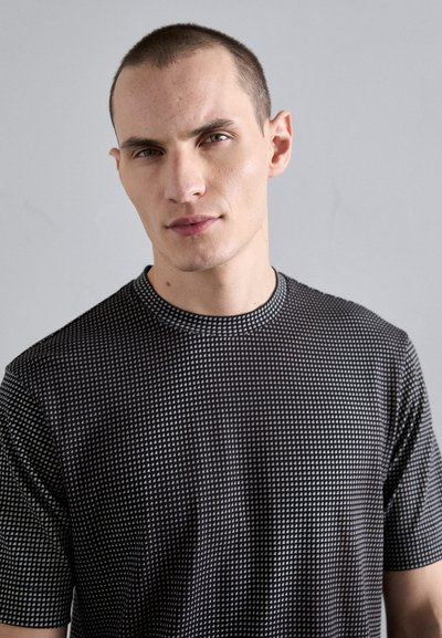 Black short-sleeve t-shirt with a geometric pattern of small white triangles, round neckline, and smooth, textured fabric.