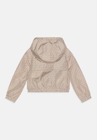 Avkortad beige jacka med huva, med ett upprepande logomönster. Långa ärmar med elastiska manschetter, lättviktigt material och avslappnad passform.