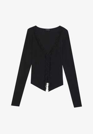 Black long-sleeve top made of soft fabric, featuring a V-neckline trimmed with lace and a cropped, pointed hemline.