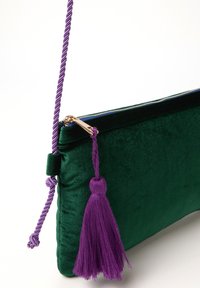 Clutch in velluto verde con chiusura con zip, dotata di una tracolla intrecciata viola e un dettaglio a frangia coordinato. Accenti in metallo dorato.