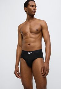 Μαύρα βαμβακερά εσώρουχα με λωρίδα μέσης με λογότυπο. Ο σχεδιασμός έχει εφαρμοστή γραμμή με ομαλή υφή και κλασικό σχήμα briefs.