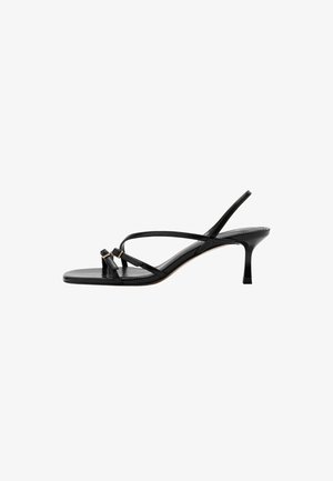 Sandale en cuir noir à fines lanières, talon stiletto bas et deux petites boucles dorées près de la bride de l’orteil.