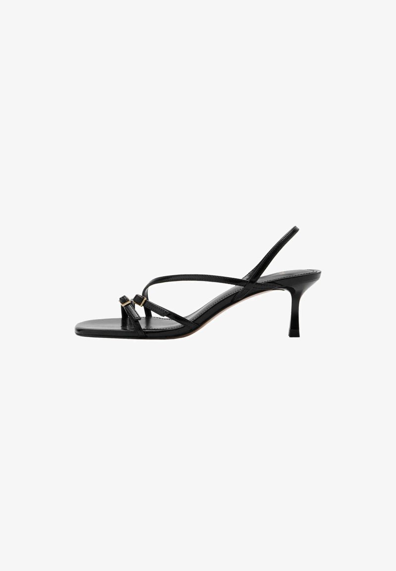 Sandale en cuir noir à fines lanières, talon stiletto bas et deux petites boucles dorées près de la bride de l’orteil.