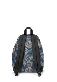 Mochila con fondo azul oscuro y patrón de hojas tropicales beige, con correas acolchadas negras y asa superior para agarrar.