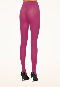 Collant fucsia con finitura semi-trasparente, design a vita alta e texture liscia, abbinati a scarpe con tacco nere.