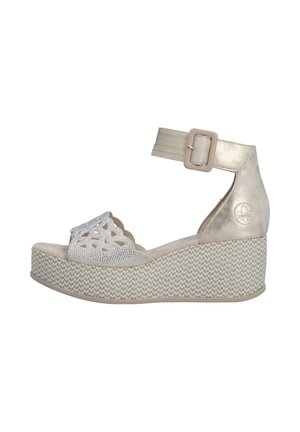 Sandale compensée beige avec bride à la cheville et boucle, partie avant perforée avec découpes décoratives et semelle plateforme texturée.