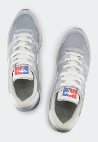 Scarpe sportive grigie con lacci bianchi, materiali in camoscio e rete, etichetta con logo sulla linguetta, linguetta e collare imbottiti, suola in gomma testurizzata.