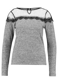 Haut gris à manches longues avec un empiècement en maille noire transparente à pois et une bordure en dentelle au niveau de l'encolure. Tissu en maille douce sur tout le vêtement.