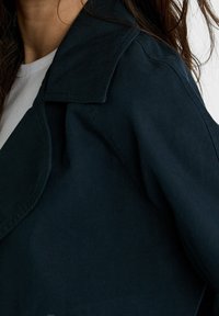 Ciemnoniebieska kurtka z wyłogami, wykonana z gładkiego materiału. Posiada dopasowany krój oraz starannie wykończone szwy.