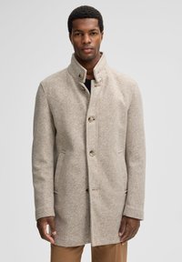 Beige herringbonejas met hoge kraag, knoopsluiting en zijzakken, gemaakt van een gestructureerde wolmixstof. Getailleerde pasvorm.