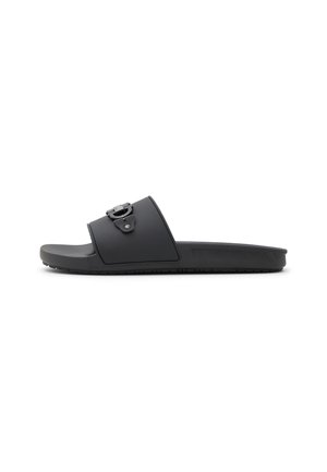 Black slide sandal with a wide strap, featuring a decorative buckle and a textured sole for grip. Made of durable, flexible material.