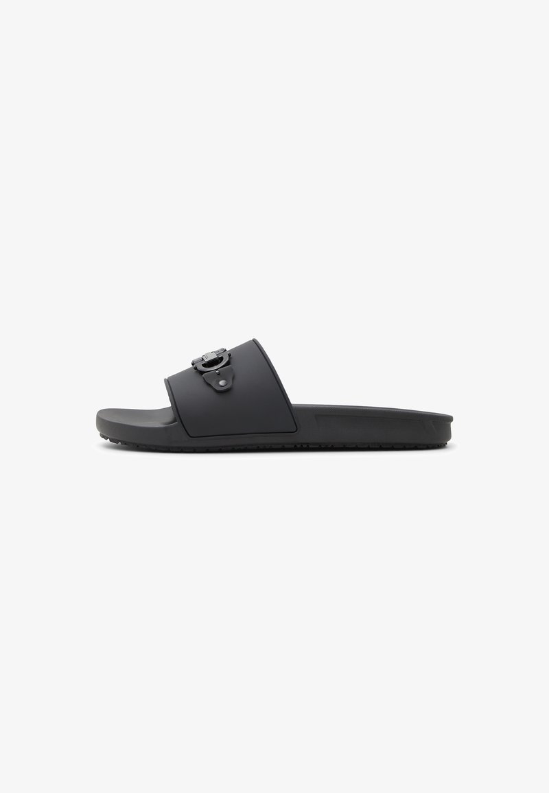 Black slide sandal with a wide strap, featuring a decorative buckle and a textured sole for grip. Made of durable, flexible material.