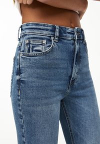 Ljusblå denimjeans med rak passform, fem fickor och midjehög midja. Har synliga sömmar och subtila urtvättning.
