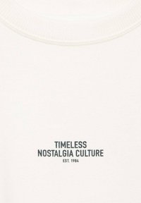White sweatshirt featuring round neck and ribbed trim. Text "TIMELESS NOSTALGIA CULTURE EST. 1984" embroidered in dark blue.