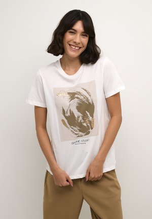 T-shirt en coton blanc à manches courtes, avec un design graphique beige aux accents dorés et un texte indiquant "GRAPHIC STUDIO". Texture lisse.