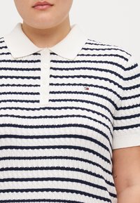 Pruhované polo tričko v bílé a námořnické modři, s texturovaným pleteným designem, s límečkem a malým logem na levé hrudi.