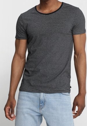 T-shirt à manches courtes à rayures noires et blanches avec un col rond, en tissu doux, associée à un jean denim bleu clair.