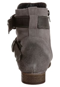 Bottine en daim gris avec un petit talon en bois, dotée de sangles en cuir foncé et d'une boucle sur le côté. Texture lisse avec un minimum de détails.