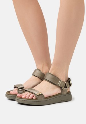 Olive green sandals with fabric straps, adjustable buckle, and a contoured footbed. Features a textured finish and low wedge sole.