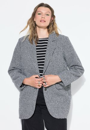 Houndstooth blazer mustassa ja valkoisena, jossa on rento leikkaus, läppäkaulus, kaksi etutaskua ja kaksinappinen kiinnitys.