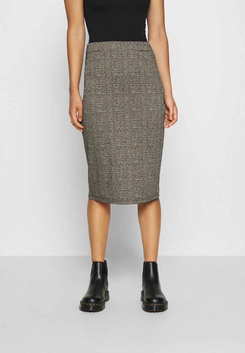 Šedá kára tužková sukně vyrobená z texturované látky, s úzkým střihem a délka ke kolenům, doplněn á černými kotníkovými botami.