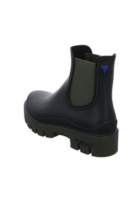 Botín Chelsea de goma negra con panel elástico verde, suela texturizada, acento triangular azul y logo en el talón.