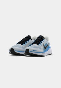 Kék és fehér sportcipők, légáteresztő hálós felsőrésszel, fekete fűzőkkel és fekete Nike pipa logóval. Jellemzője a párnázott talp és a mintázott talprésze.