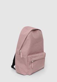 Zaino in tessuto rosa con parte superiore arrotondata, tasca frontale, doppi cursori e spallacci neri. Design semplice, senza motivi o dettagli visibili.