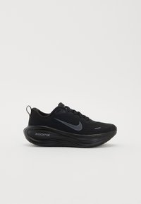 Svart atletisk sko med en texturerad övre del, med en framträdande vit Nike swoosh. Rund sula märkta "zoomx" för dämpande stöd.
